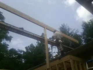 Carpenter setting a ridge beam over a new addition frame — Ice Dam Removal by Roofing Brothers in Saint Donatus