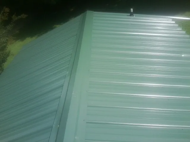 New green metal panels meeting at the ridge of a roof — Flat Roof Repair work by our crew in Saint Donatus