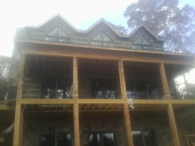 Dormers and porch framing on a large log home under construction — Roof Coating work by our crew in Saint Donatus