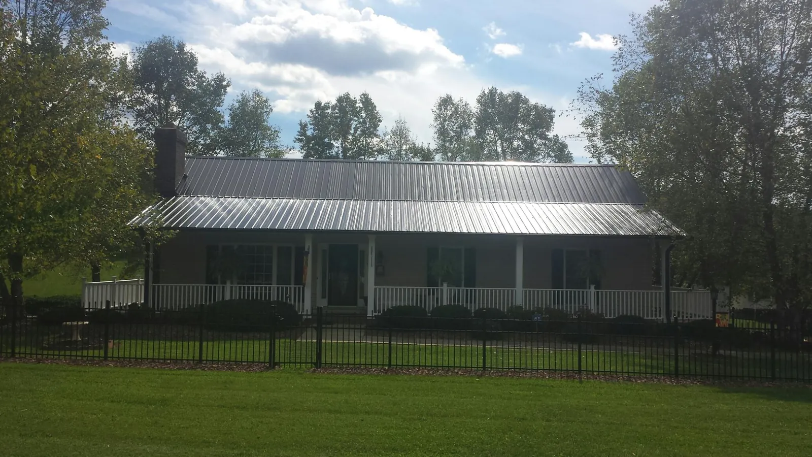 Gray metal roof on a brick ranch with a full width front porch — Gutter Guard Installation work by our crew in Saint Donatus