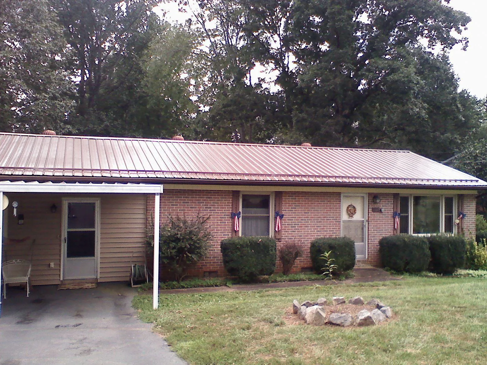 Bronze metal roof and carport on a brick ranch home — Roof Repair work by our crew in Saint Donatus