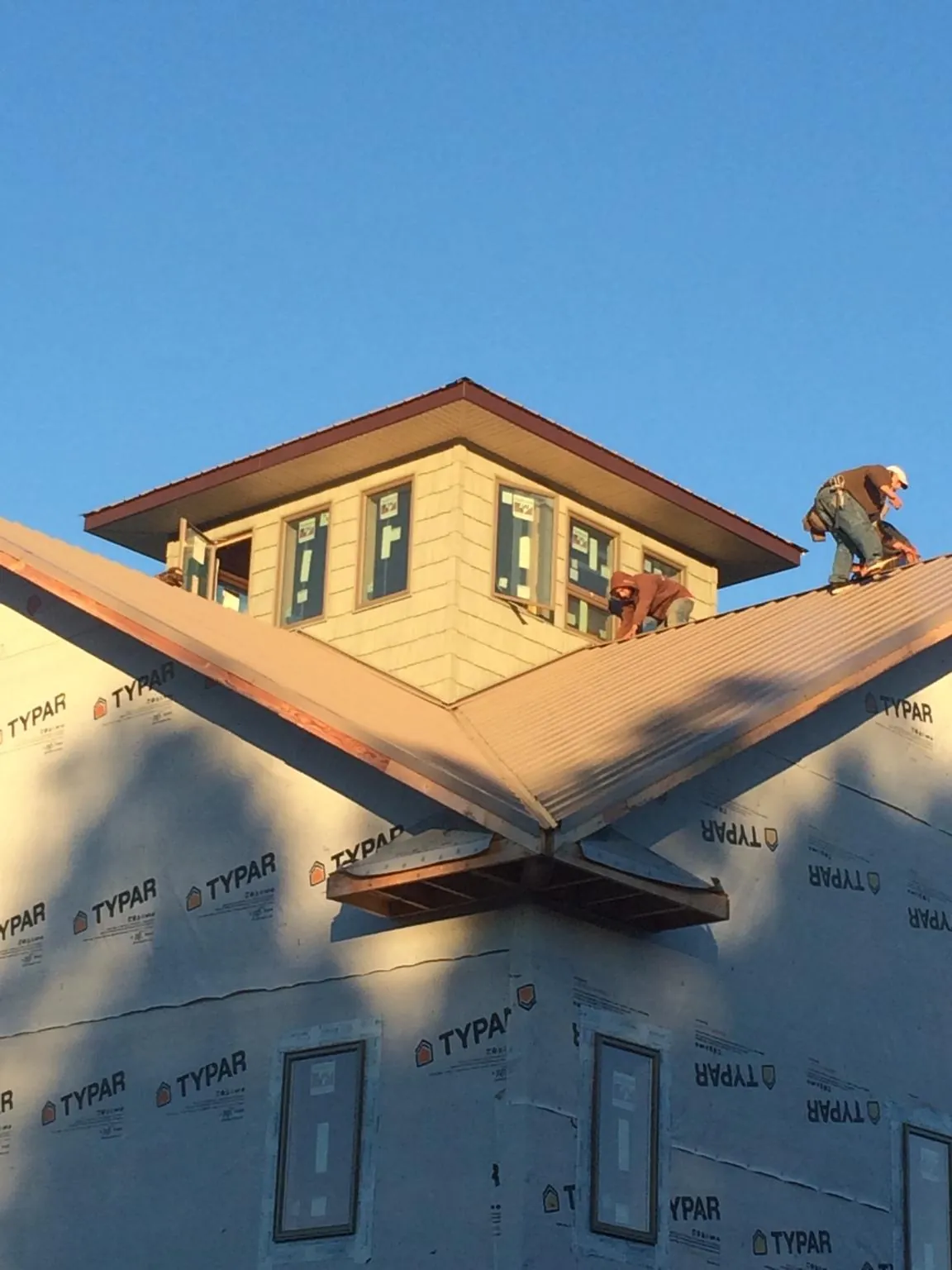 Roofers working around a rooftop cupola on a new metal roof at sunset — Roof Waterproofing in Saint Donatus by Roofing Brothers